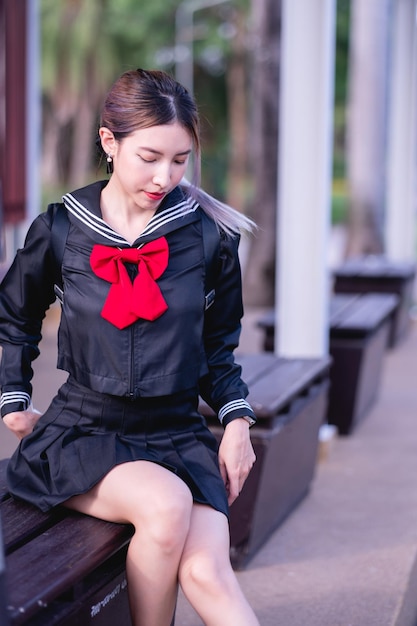 Woman wearing cosplay Japanese school uniform sitting at bus stop