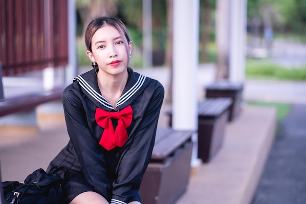 Woman wearing cosplay Japanese school uniform sitting at bus stop