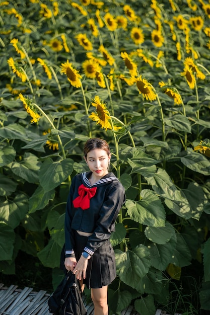 Woman wearing cosplay Japanese school uniform at sunflower garden outdoor