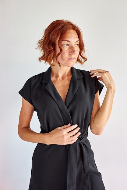 Woman wearing dress isolated in studio, beautiful redhead woman with freckles posing, puts on dress, preparing