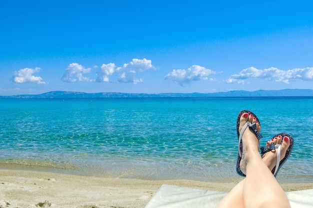 Woman wearing flipflops laying on the sunbed near the ocean on a beach