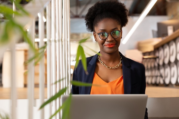 Woman wearing glasses. Beautiful dark-skinned woman wearing glasses working in laptop