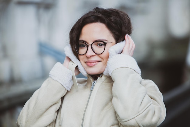 A woman wearing glasses and a coat with a white glove on her head.