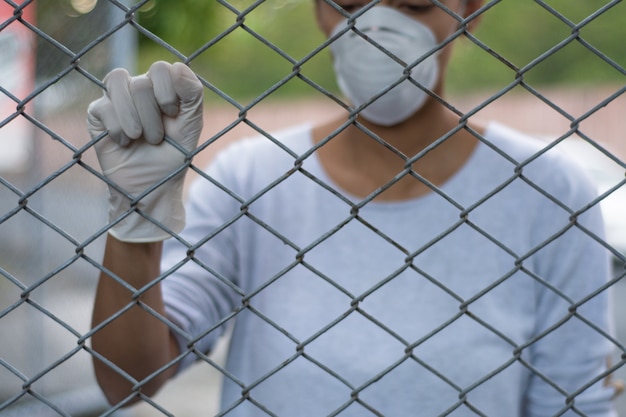 Woman wearing gloves and face mask behind fence