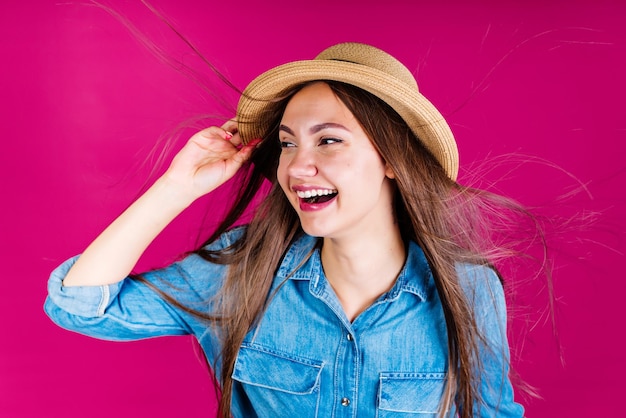 A woman wearing a hat and a denim shirt smiles and smiles.