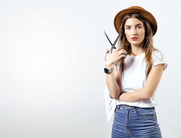 A woman wearing a hat looking through scissors hight quality