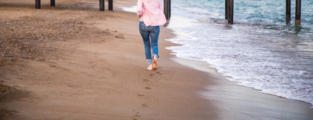 Woman wearing jeans running at sunet on the beach sand