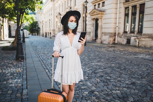 Photo woman wearing mask using smart phone standing on road