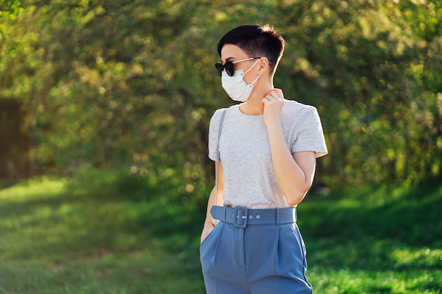 Woman wearing medical mask, alone walks in the park during Covid 19 outbreak. Protection in prevention for coronavirus. Social Distancing concept.