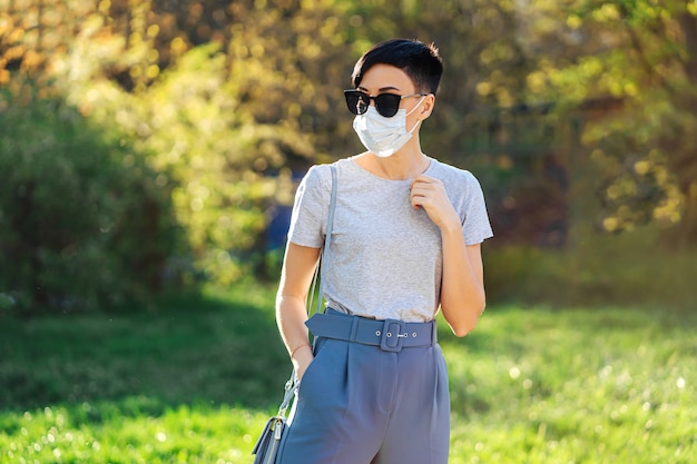 Woman wearing medical mask, alone walks in the park during Covid 19 outbreak. Protection in prevention for coronavirus. Social Distancing concept.