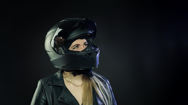 A woman wearing a motorcycle helmet on a dark background The concept of space