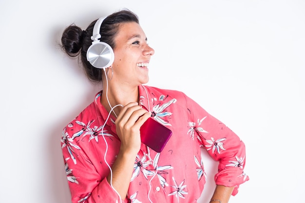 A woman wearing a pink shirt with a white headphone and a pink floral print happy