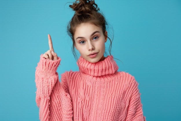 Photo a woman wearing a pink sweater points upwards possibly indicating direction or excitement