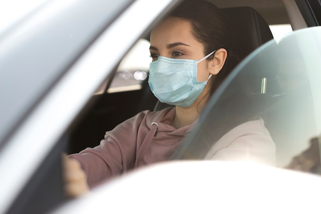 Woman wearing protection mask in car