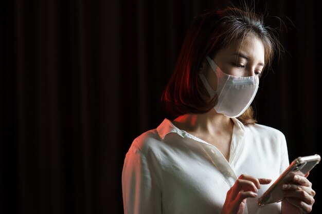 Woman wearing protective mask and uses smartphone