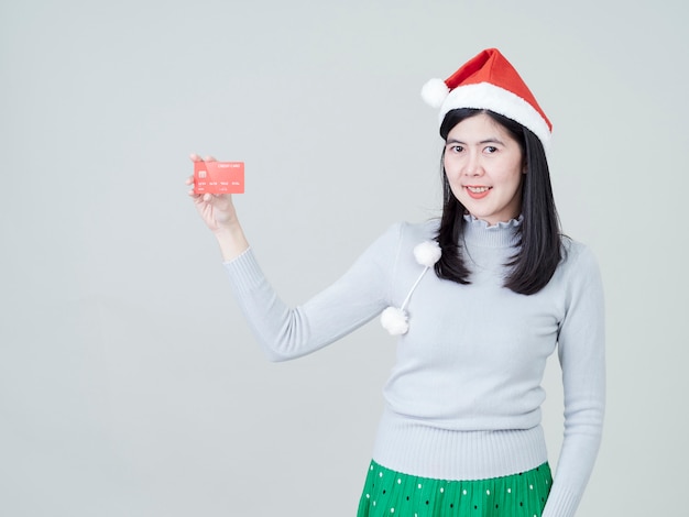 Woman wearing santa hat in hand showing credit cards shopping