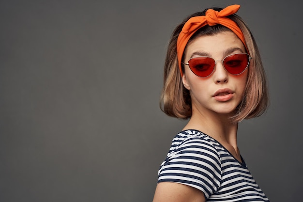 Woman wearing sunglasses with orange bandage on head isolated background fashion