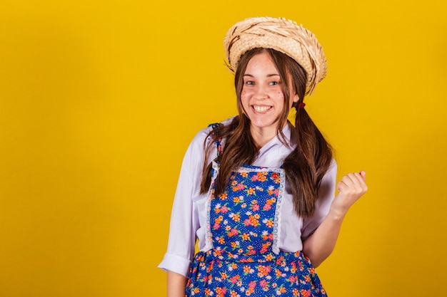 Woman wearing typical clothes for the Festa Junina calling with your hands inviting come here