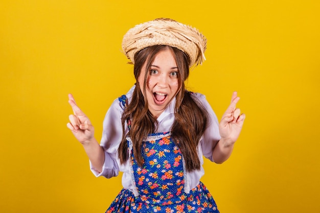 Woman wearing typical clothes for the Festa Junina Fingers crossed luck wishing hoping