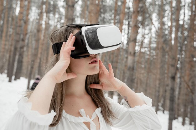 Photo woman wearing virtual reality simulator against trees outdoors