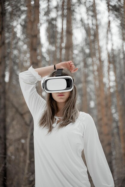 Photo woman wearing virtual reality simulator against trees outdoors