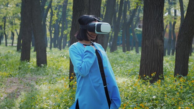 Photo woman wearing virtual reality simulator while standing on field at forest