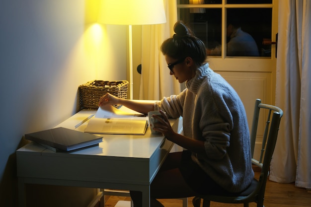 Woman wearing a warm woolen sweater is reading book