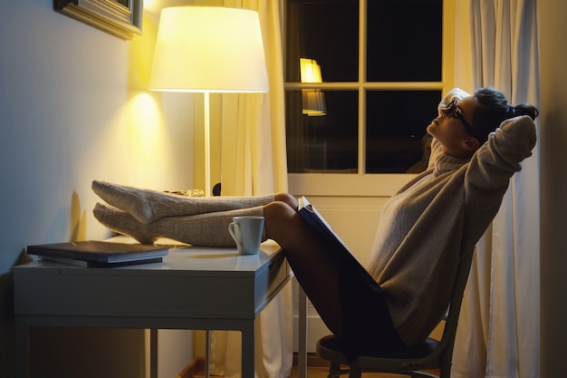 Woman wearing a warm woolen sweater is reading book