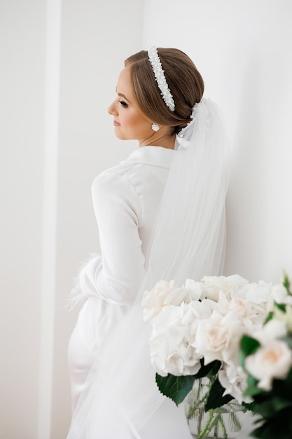 Photo a woman wearing a white dress and a white headband stands in front of a wall