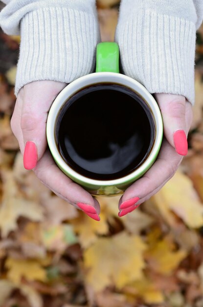 Woman wearing white sweater holding a green coffee cup