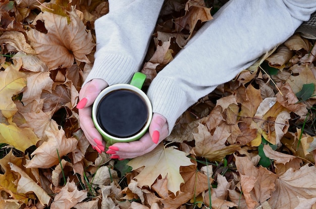 Woman wearing white sweater holding a green coffee cup