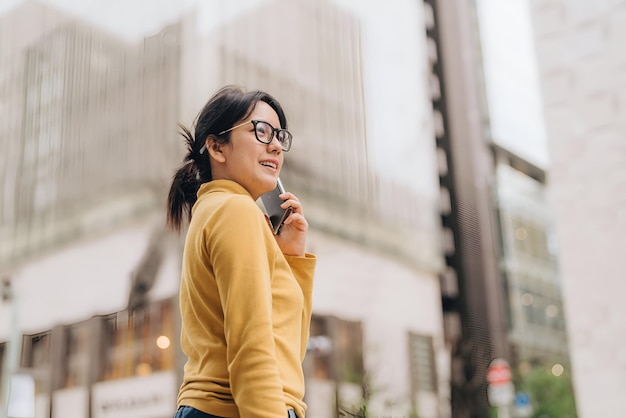 a woman wearing a yellow sweater is talking on a cell phone