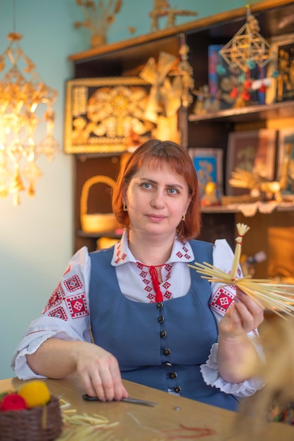 Woman weaves various toys and clothes from straw