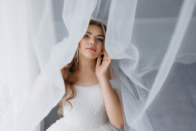 Photo a woman in a wedding dress is standing in front of a curtain