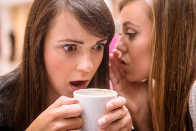 Woman whispering in her friends ears