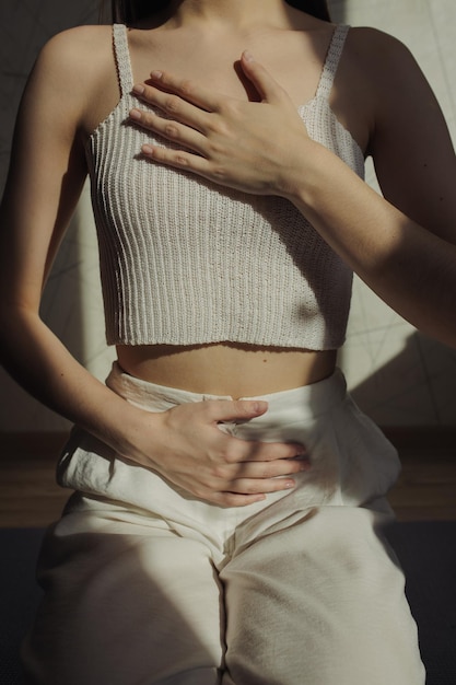 woman in white clothes touching chest and stomach while breathing during yoga meditation