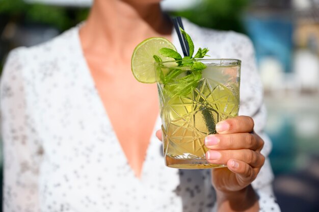 Woman in white dress drinking a mojito cocktail