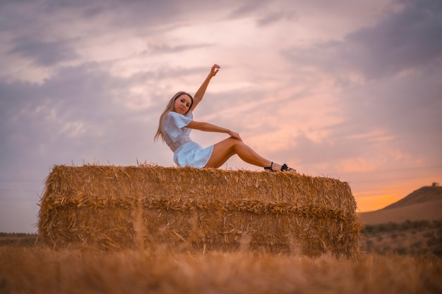 Woman in a white dress in a field of dry straw