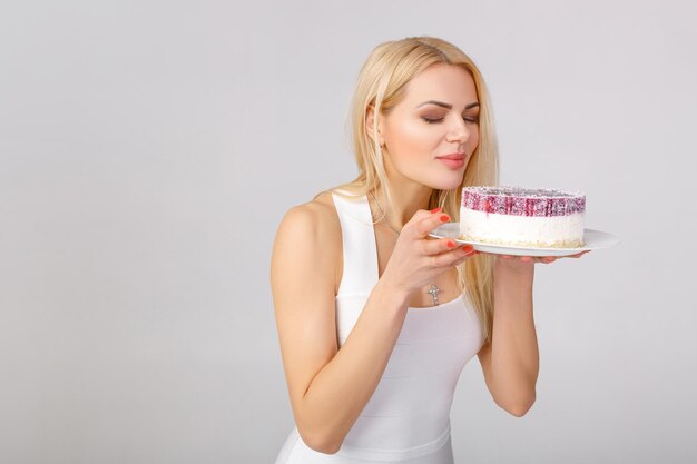 Woman in white dress holding cake