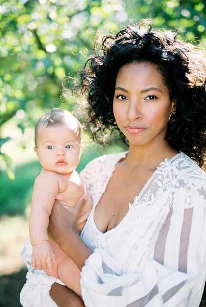 Woman in a white dress with a newborn in her arms