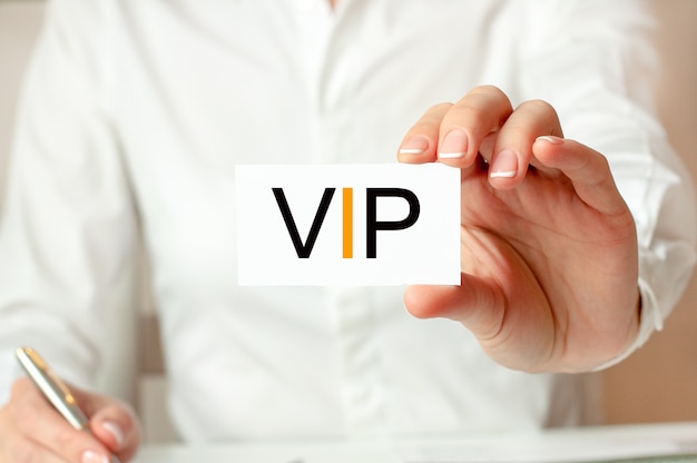 A woman in a white shirt holds a piece of paper with the text: VIP. Business concept for companies. VIP - short for Very Important Person.