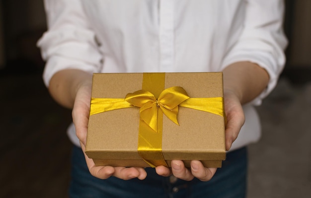 A woman in white shirt and jeans holds gift for holiday Gift greeting for holiday Valentines Day