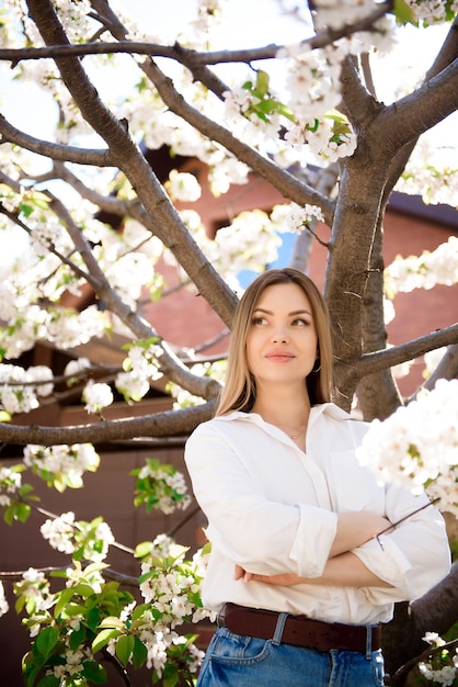 A woman in a white shirt and jeans in a spring garden