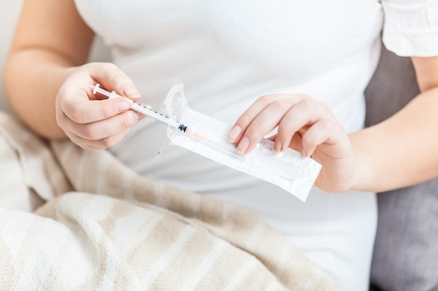 Woman in white shirt opening single use syringe