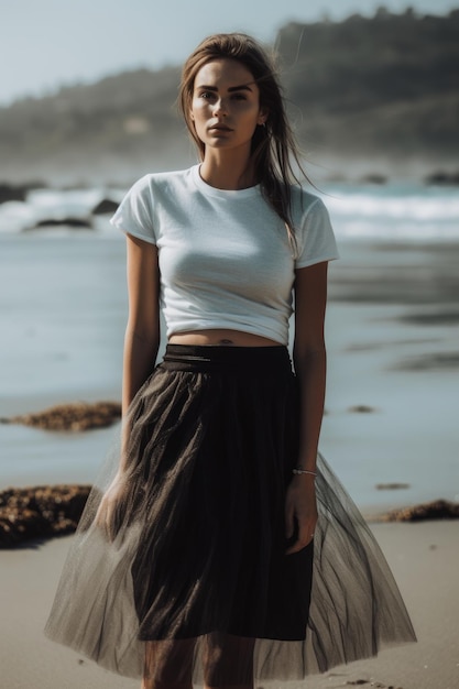 A woman in a white shirt stands on a beach wearing a black skirt.