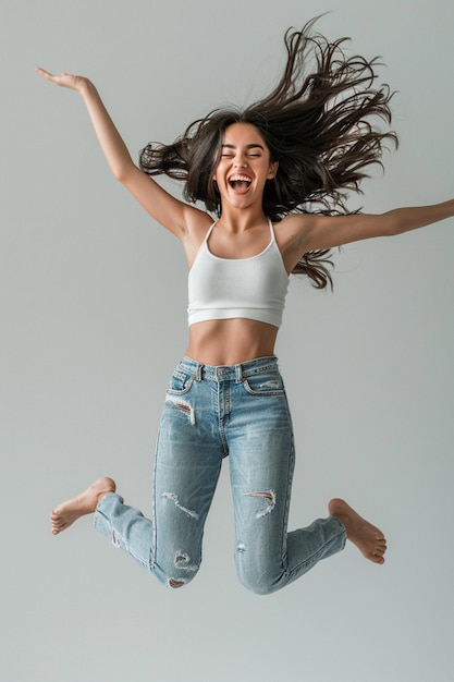 a woman in a white tank top is jumping in the air with her arms outstretched