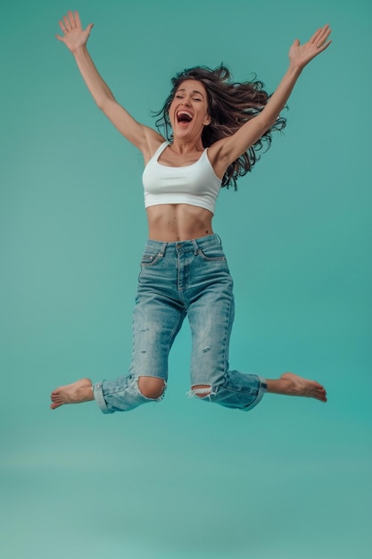 a woman in a white tank top is jumping in the air with her arms up in the air