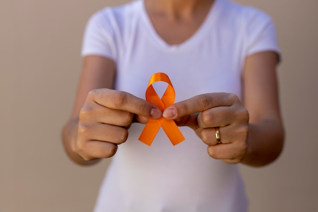 Woman in white tshirt holding orange ribbon skin cancer prevention campaign