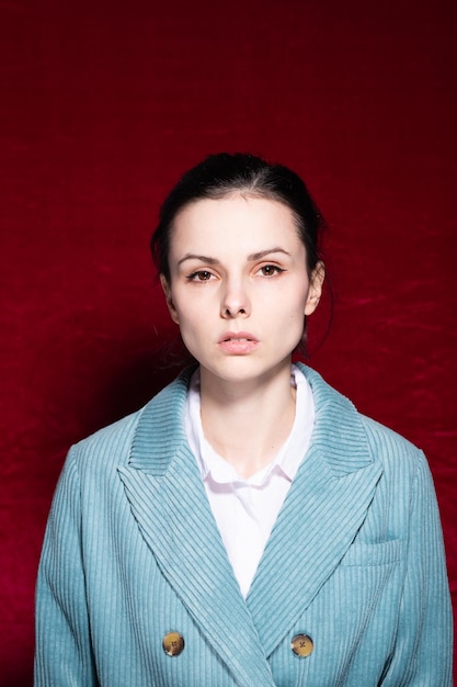 woman in white Tshirt and velvet blue jacket red background High quality photo