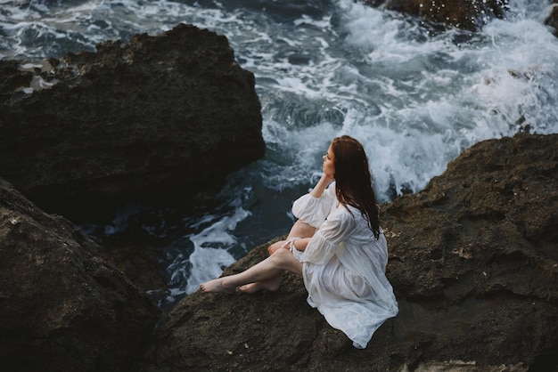 Woman in white wedding dress barefoot sitting on a stone nature High quality photo